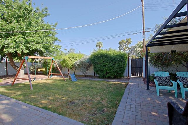 Grassy backyard with swing set and shaded seating