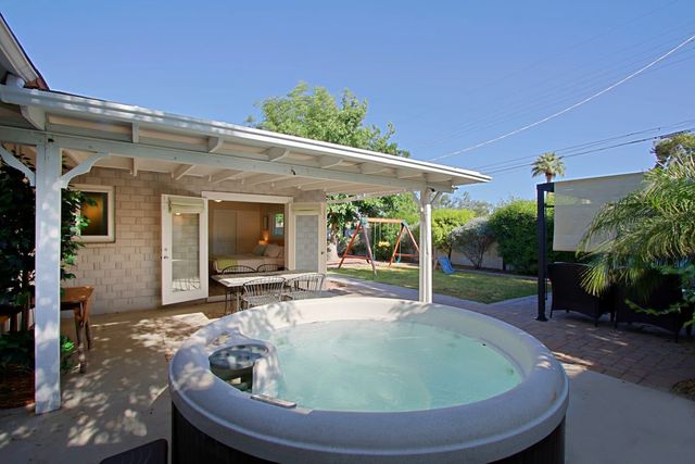 Hot tub on the covered patio with the backyard behind it